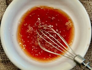 Mignonette Sauce For Oysters being whisked in a bowl with red wine vinegar and finely chopped shallots.