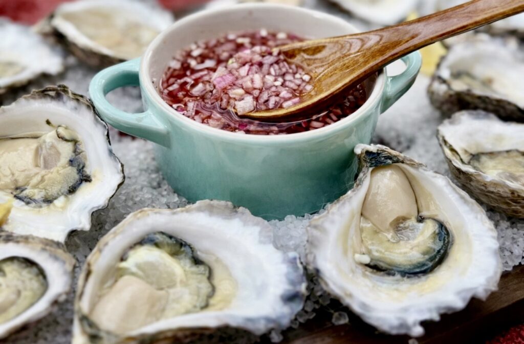 Fresh oysters on the half shell topped with Mignonette Sauce For Oysters and presented on rock salt