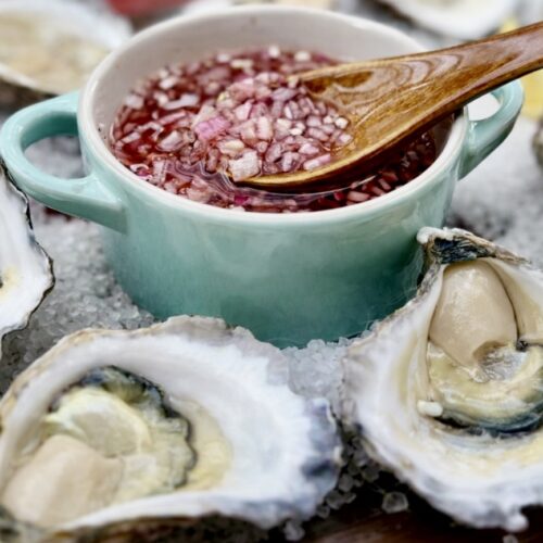 Fresh oysters on the half shell topped with Mignonette Sauce For Oysters and presented on rock salt