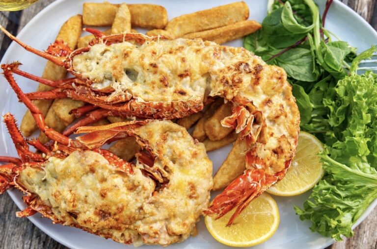 Easy lobster mornay served in the shell with golden cheesy sauce, chips, fresh salad and lemon wedge