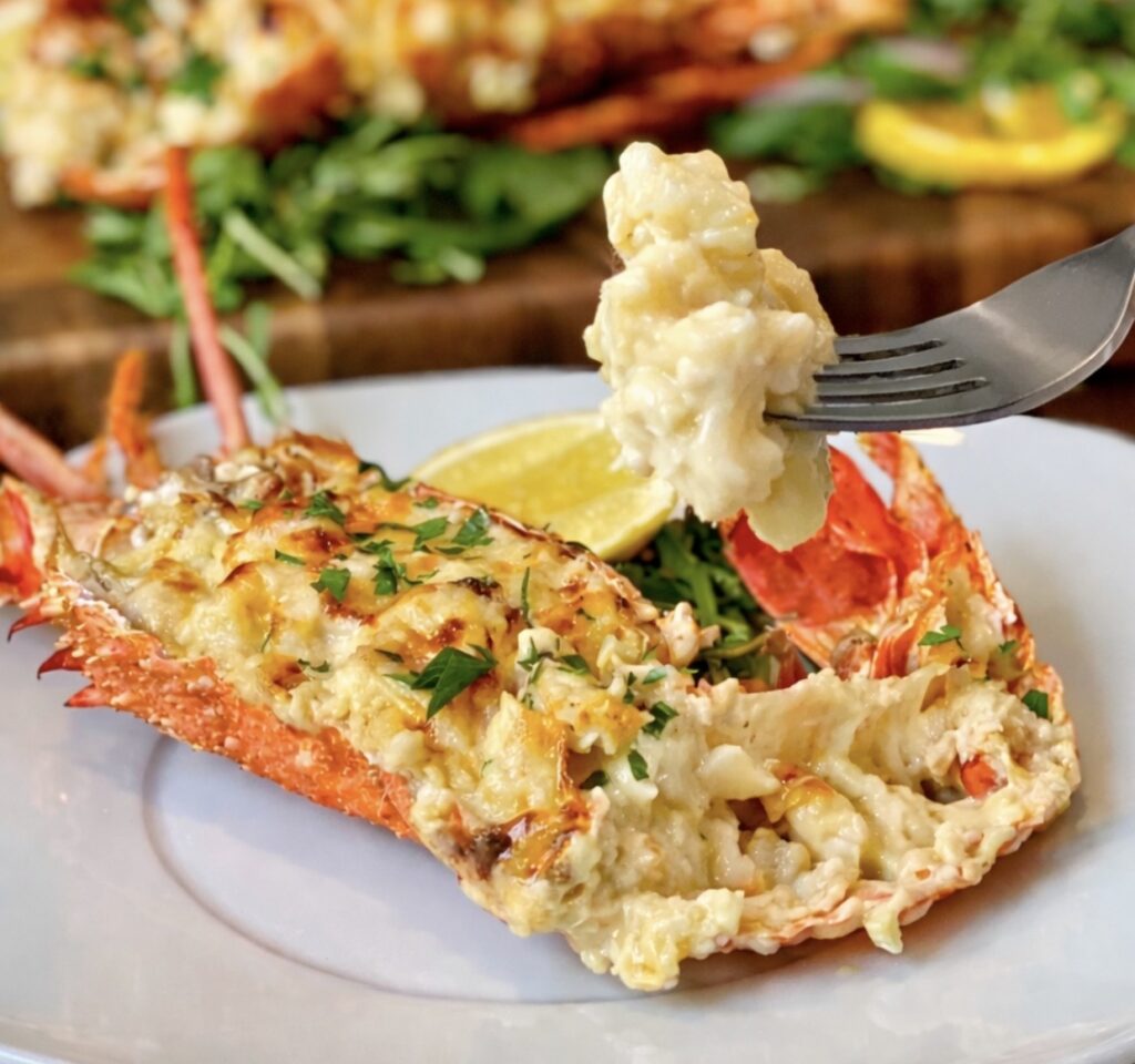 Creamy lobster mornay close-up showing tender lobster meat lifted with a fork and coated in rich cheesy sauce