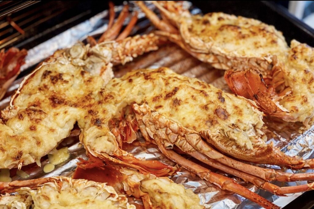 Lobster mornay baking under the grill with bubbling golden cheese sauce in the lobster shell