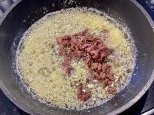 Anchovy fillets melting into butter and garlic to create a savoury base for breadcrumbs