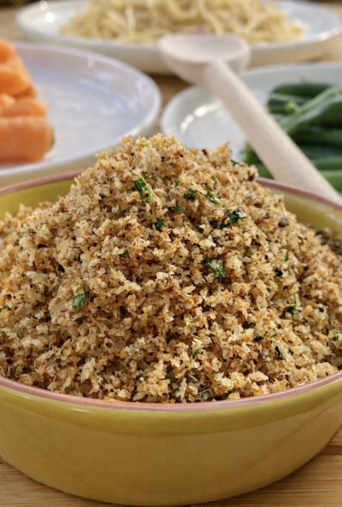 Close-up of crispy anchovy breadcrumbs with herbs in a yellow dish