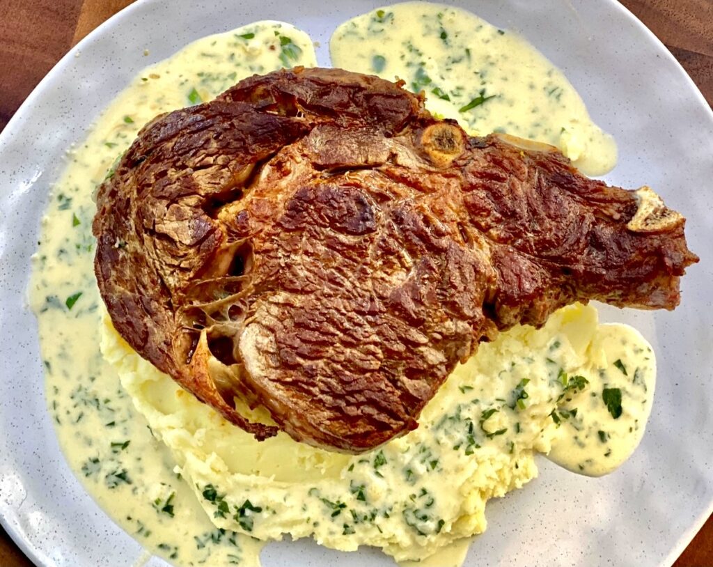 Cooked steak over a generous amount of creamy garlic sauce