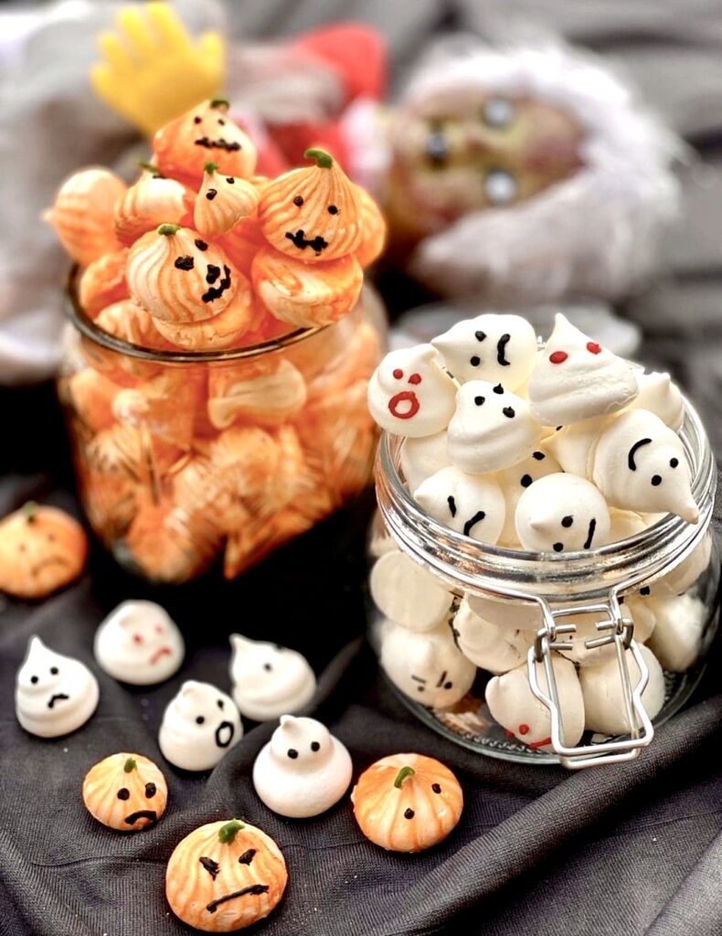 Halloween meringue cookies in glass jars featuring ghost and pumpkin shaped meringues