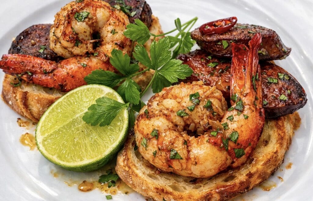 Garlic prawns and chorizo served on toasted bread with parsley and fresh lime