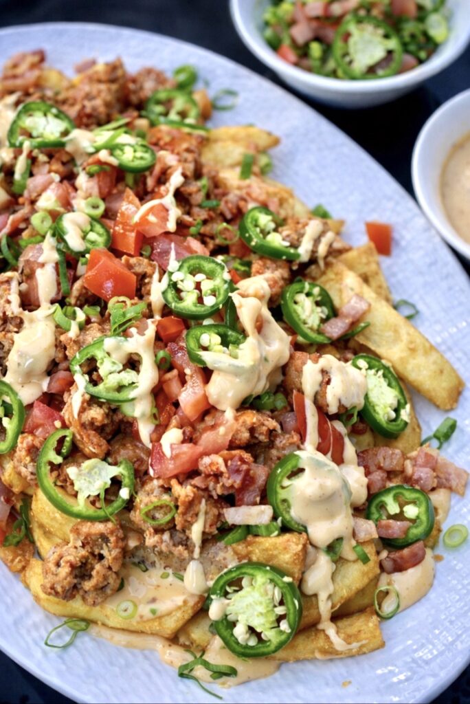 Crispy loaded fries topped with sausage, bacon, sliced jalapeños and diced tomatoes drizzled with cheesy sauce.