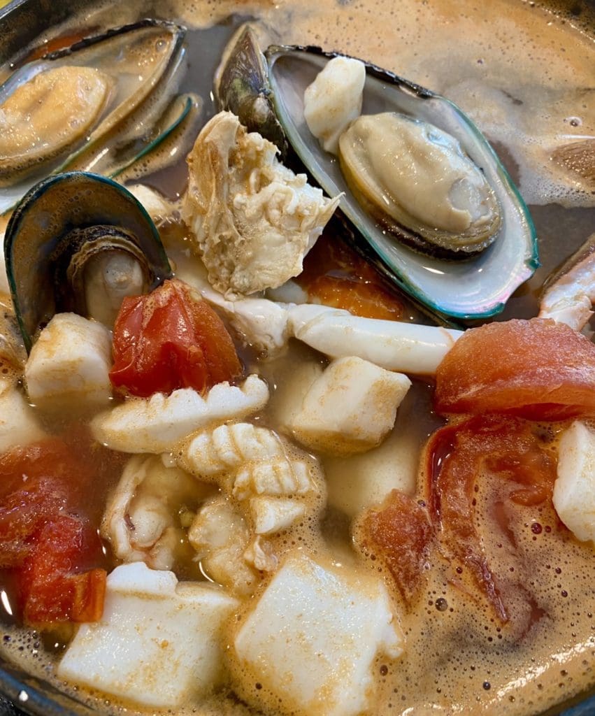 Adding mussels, squid, and fish into the spicy and sour Thai Seafood Soup