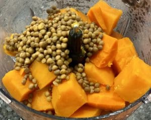 Placing the steamed sweet potatoes, carrots and lentils into a food processor to make baby puree