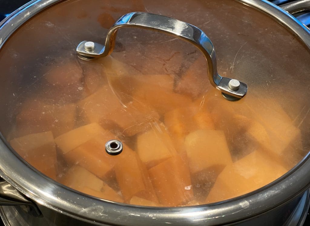 Steaming the chopped sweet potatoes and carrots with the lid on until they're soft to make lentils for baby