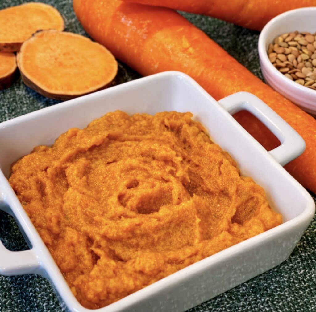 Smooth lentils for baby blended with sweet potato and carrot served in a white dish