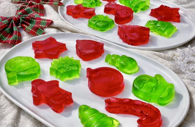 Holiday finger jello assortment in red and green, set on white serving platters for a festive dessert display