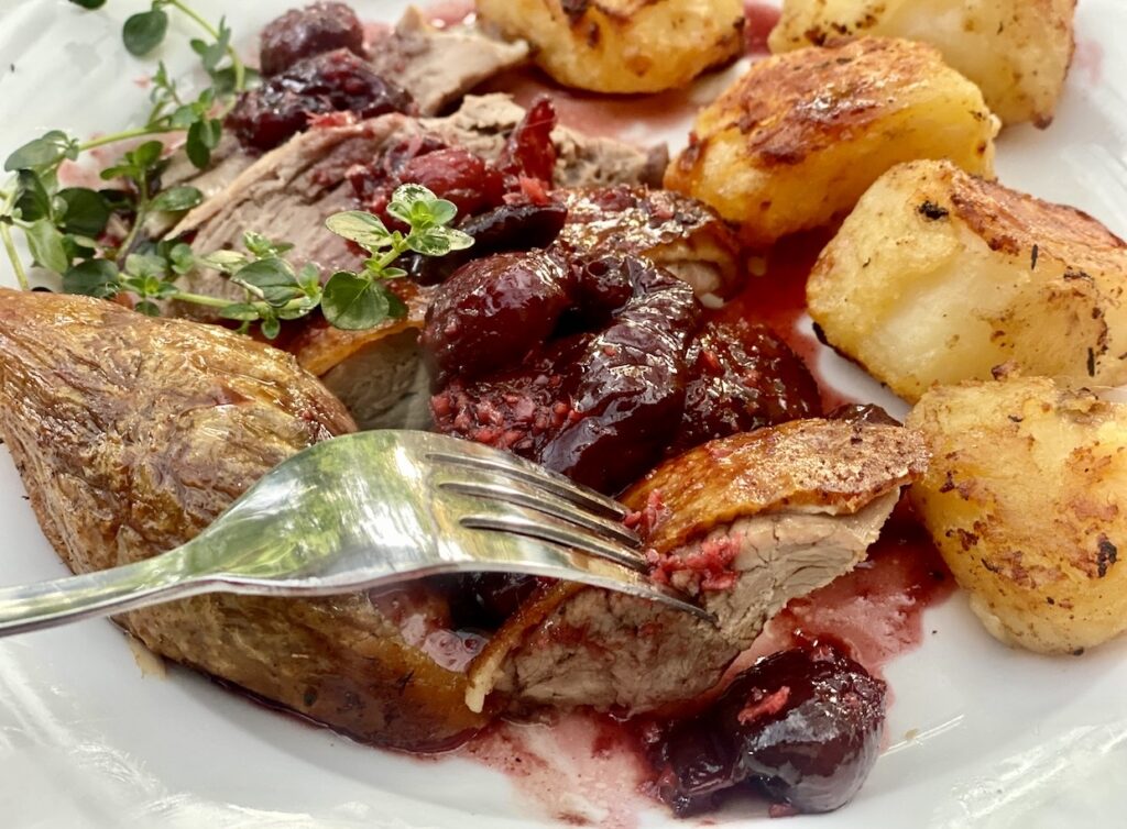 Savoury cherry sauce served over roasted duck breast with crispy roast potatoes and fresh thyme