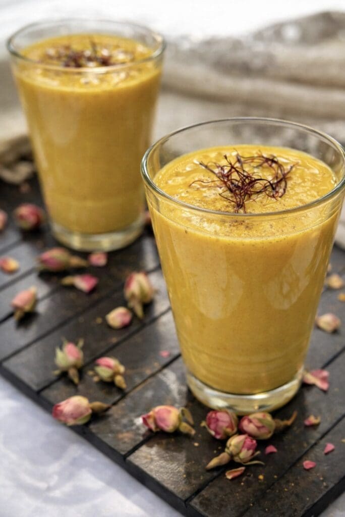 Homemade mango lassi cocktail served in glass cups with saffron on top