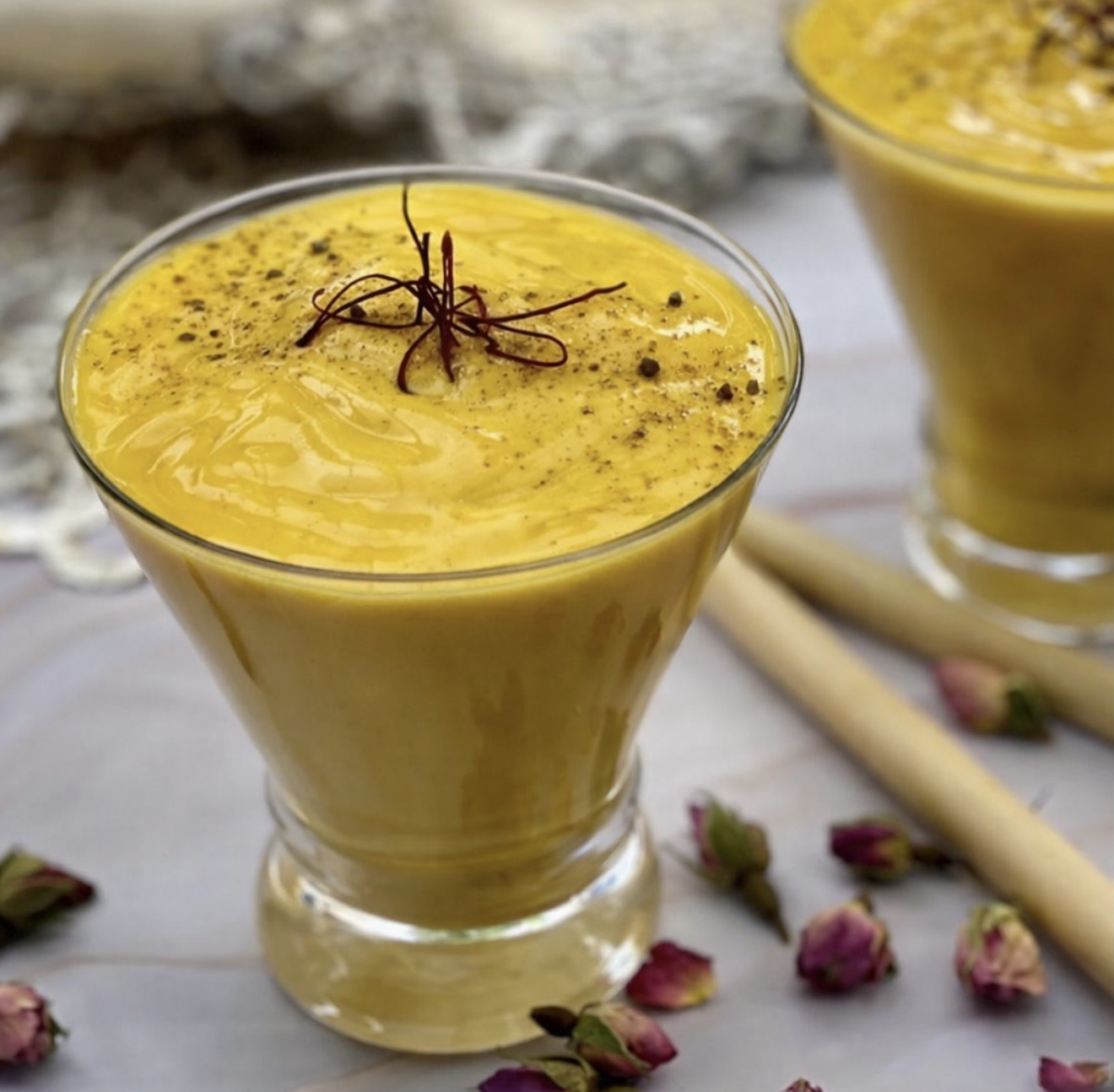 Refreshing mango lassi cocktail made with ripe mango and yoghurt in two glasses