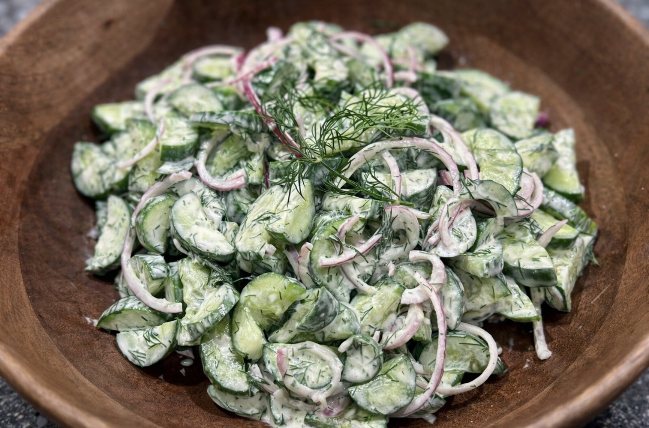 Creamy Cucumber Salad served in a wooden bowl with sliced cucumbers, red onion and fresh dill