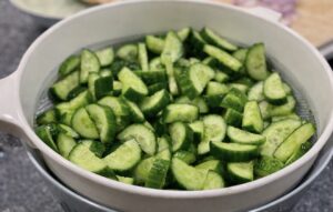 Freshly sliced cucumbers draining in a colander for Creamy Cucumber Salad