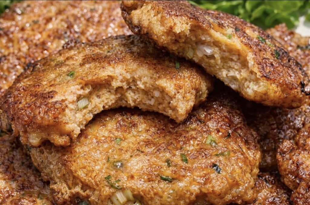 Thai Fish Cakes with Prawns broken open to reveal juicy prawn and fish filling with fresh herbs.