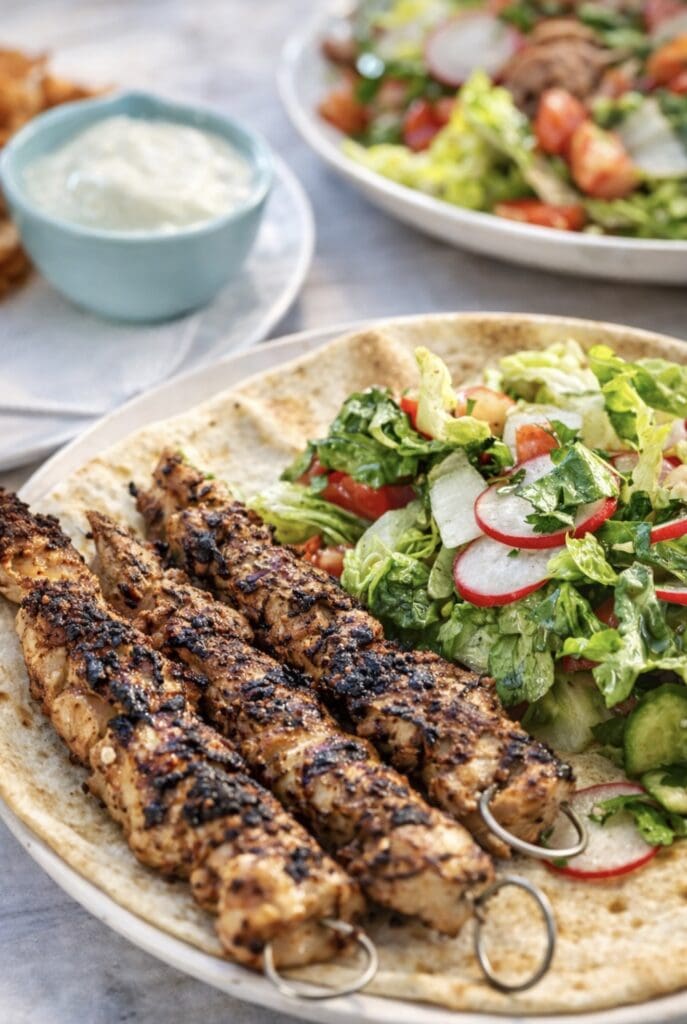 Juicy grilled shish tawook chicken skewers with Middle Eastern salad on flatbread