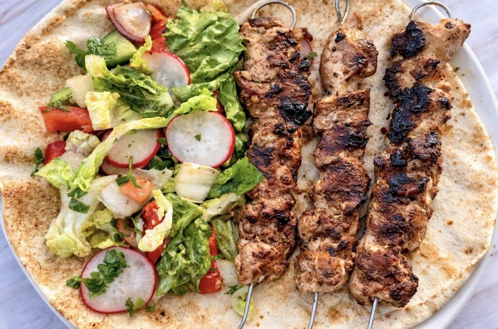 Shish tawook Middle Eastern chicken skewers served on warm flatbread with fresh salad and grilled chicken