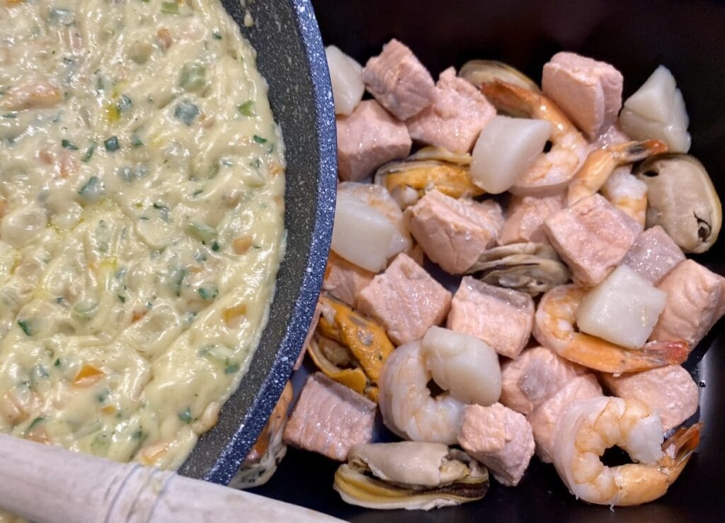 Covering the poached seafood with the creamy white sauce