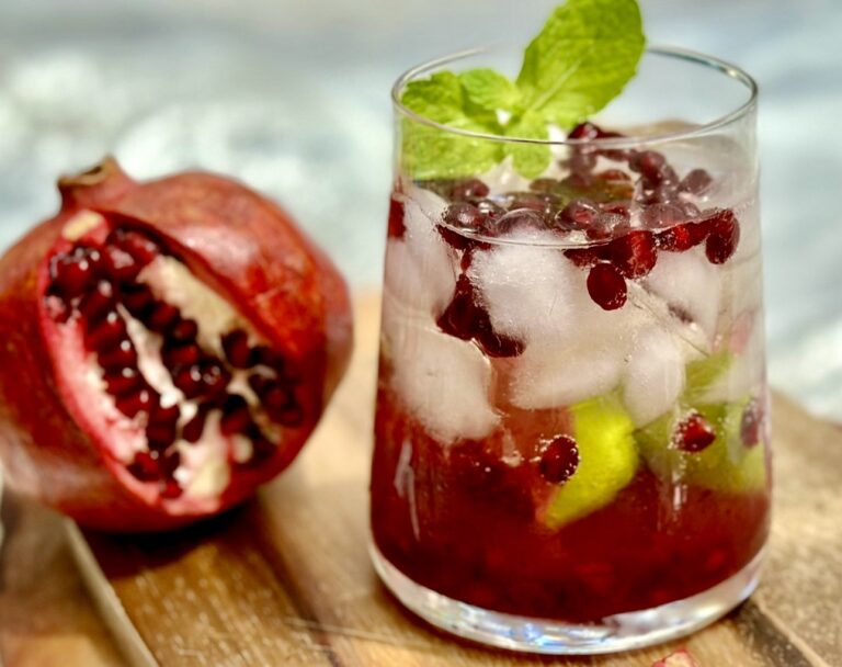 Pomegranate cocktail with fresh pomegranate seeds, ice, and mint in a glass