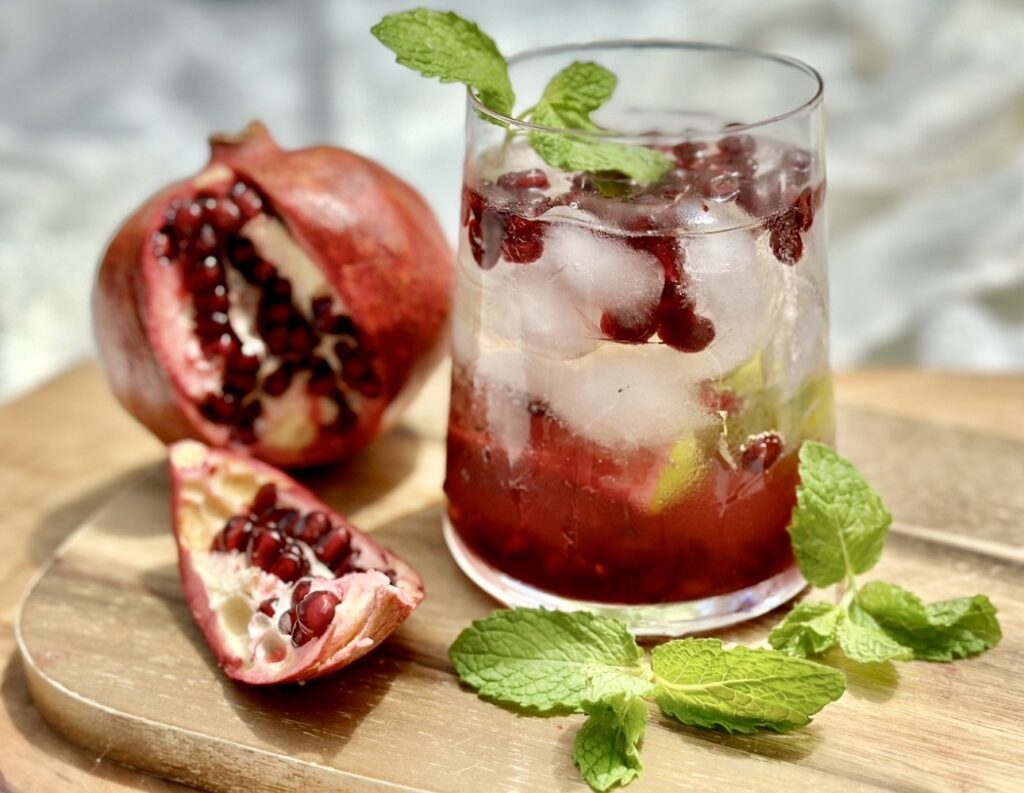 Close up of a pomegranate cocktail with mint garnish and sparkling ice