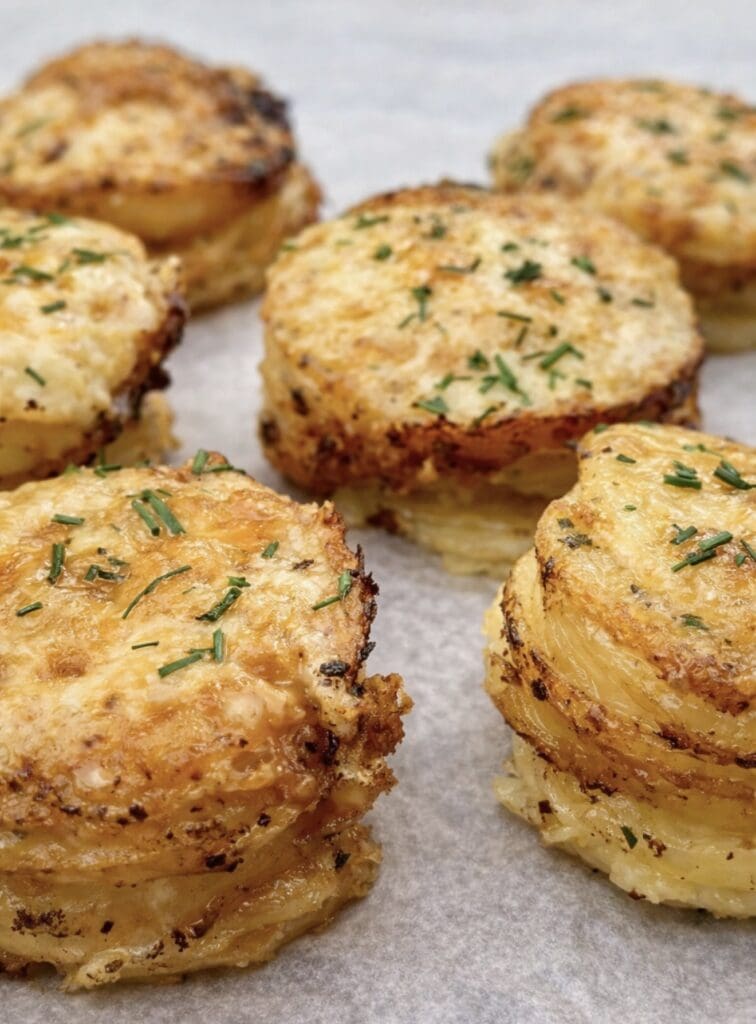 A close-up shot of a tray of potato stacks out of the oven looking rich, golden with loads of melted cheese