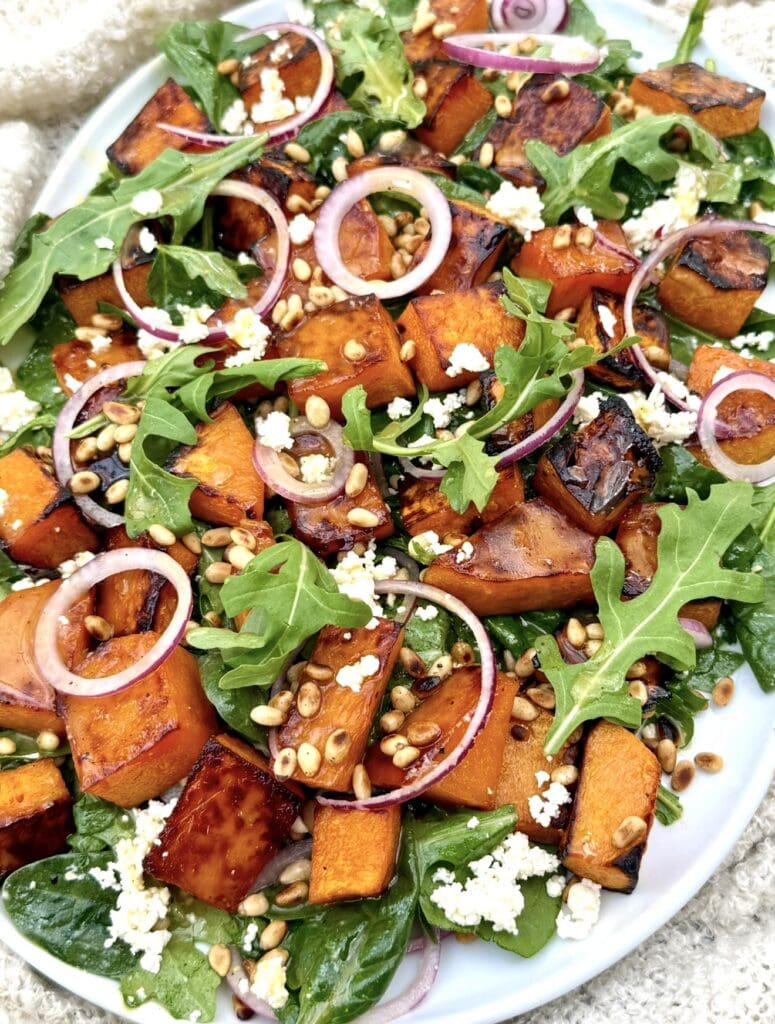 Roast pumpkin salad served on a platter with honey roasted pumpkin, feta, and pine nuts
