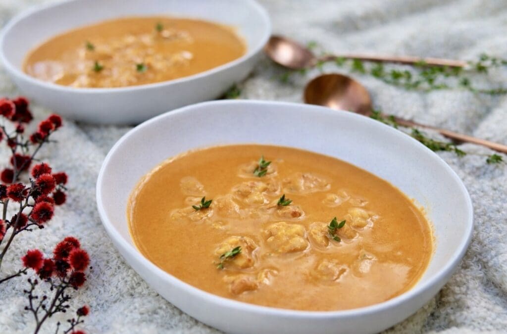 Creamy prawn bisque served in white bowls, garnished with tender prawns and fresh thyme.