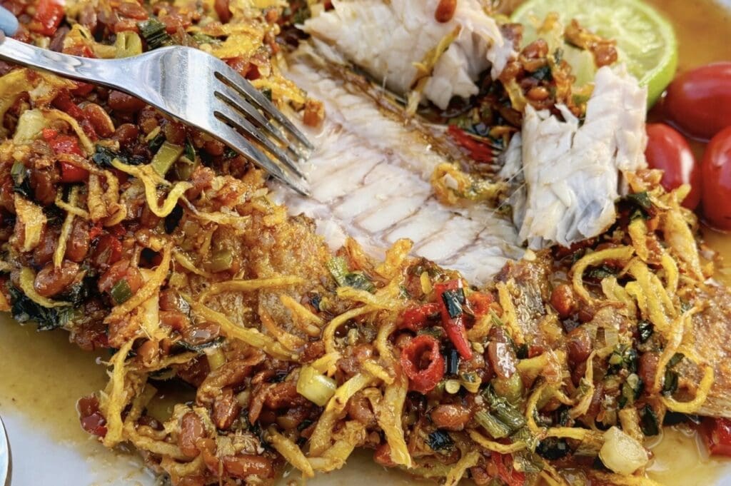 Close up look at Crispy fried fish with ginger, spring onion and chilli in a savoury Cambodian soybean sauce.