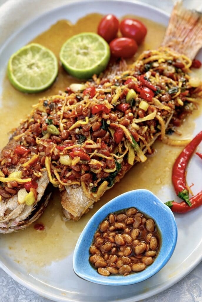 Asian-style fried whole fish covered in ginger and chilli sauce, plated with lime and fresh red chilli.
