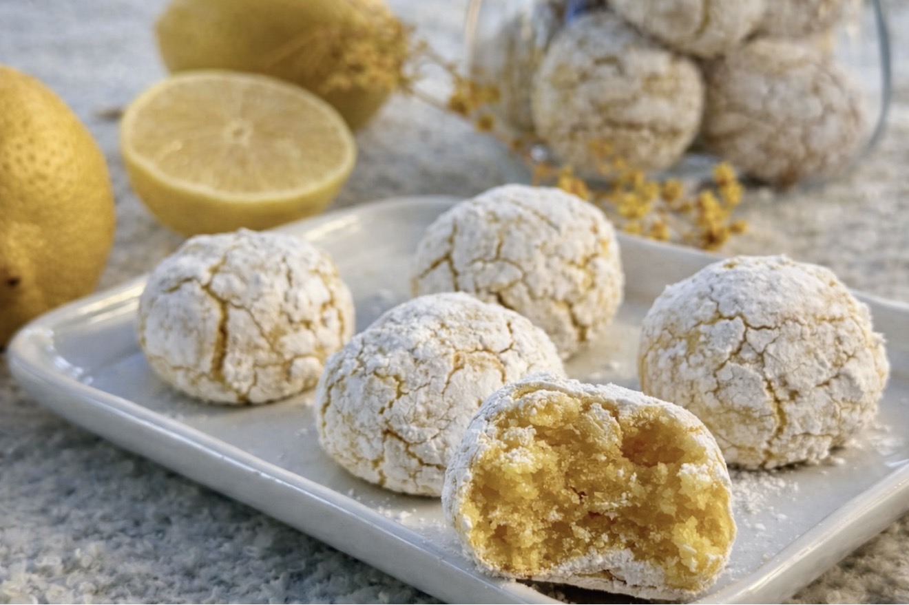 Crispy chewy Lemon Amaretti cookies on a plate with one bitten showing the inside