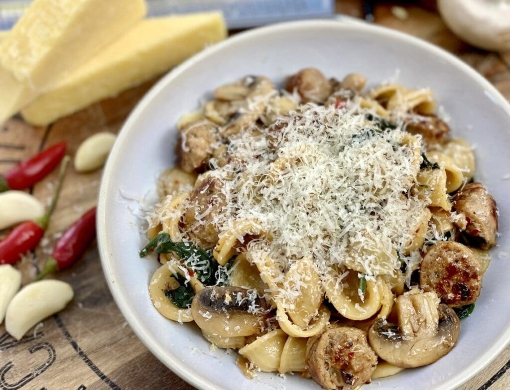 Spicy sausage pasta with orecchiette, mushrooms, spinach with shredded parmesan on top