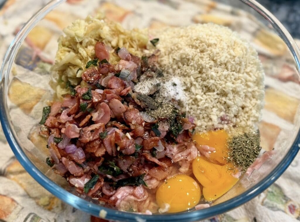 A big glass bowl holds the pork and apple sausage rolls filling ingredients.