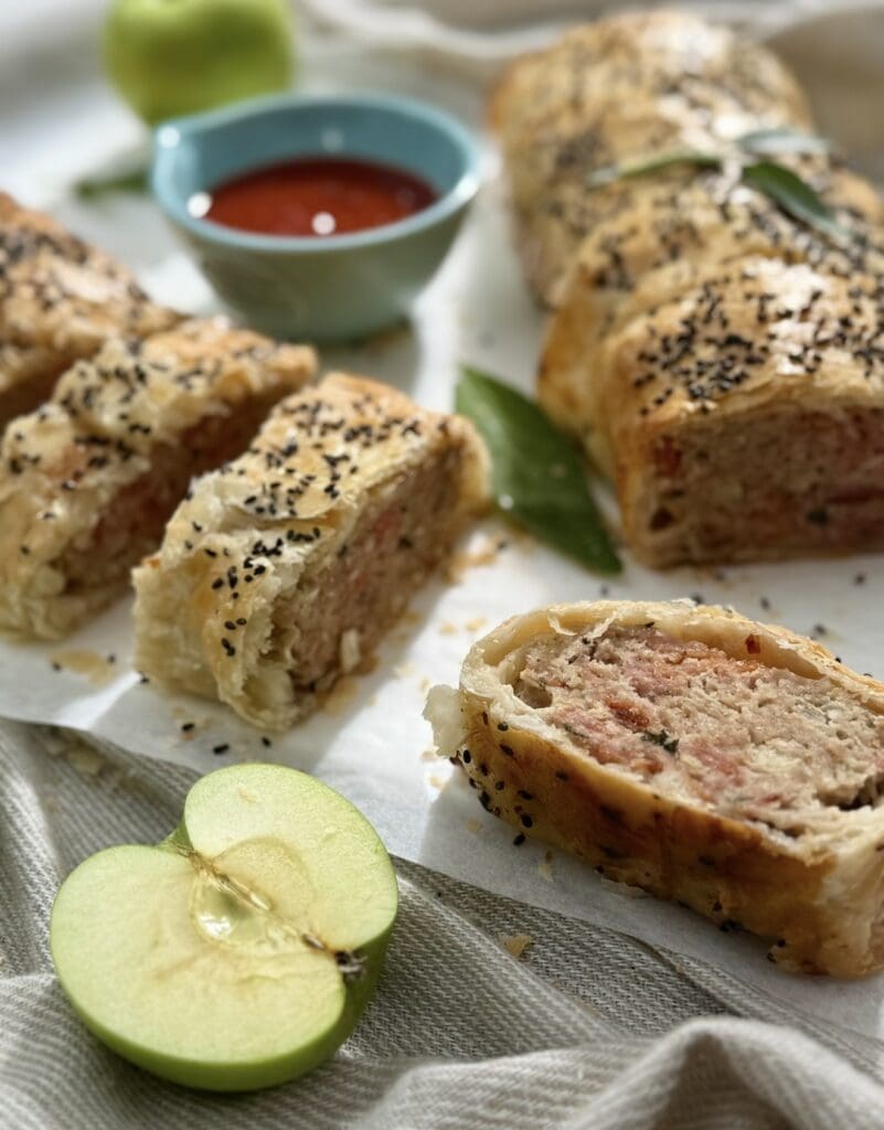 The close-up image displays the filling of Pork and Apple Sausage Rolls after being sliced.