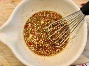 A whisk blending the marinade ingredients together