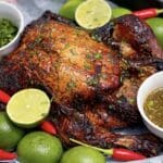 Whole roast chilli lime chicken with crispy skin, served with fresh limes, red chillies and herb sauce