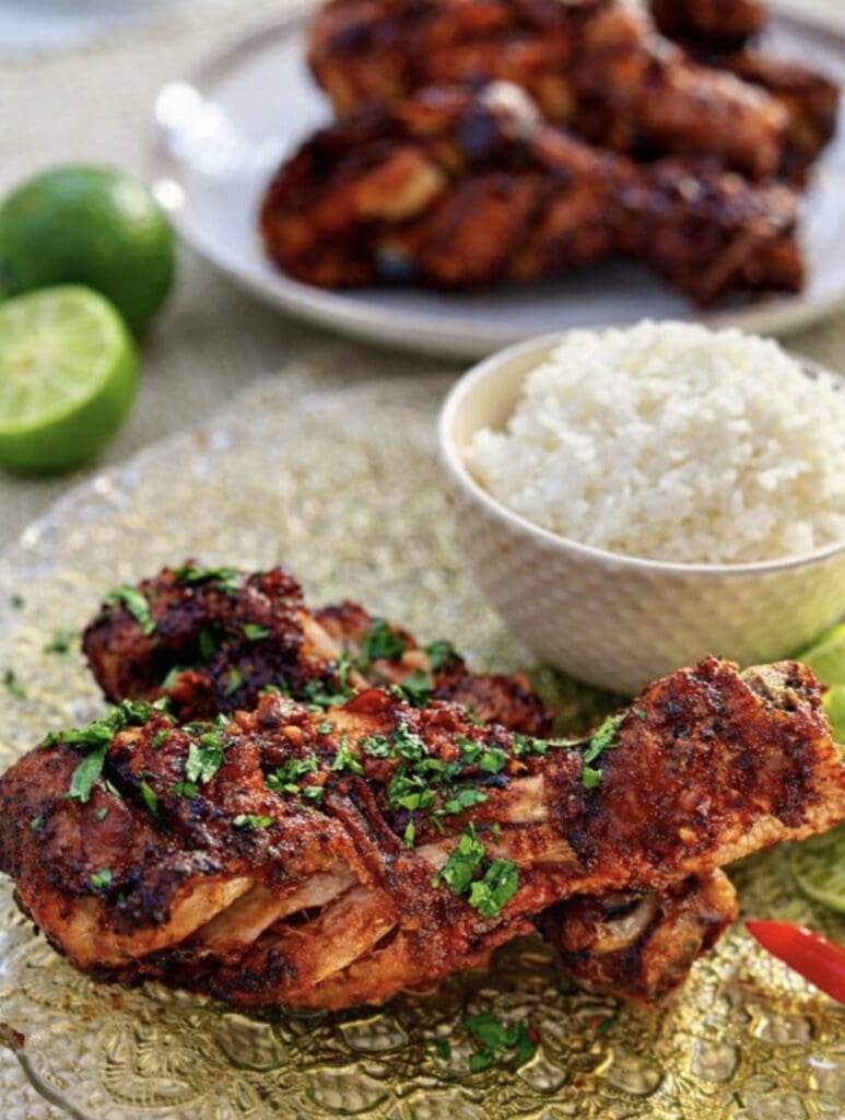 A close up of Thai Red Curry Roast Chicken drumsticks served on a plate with rice, with rice