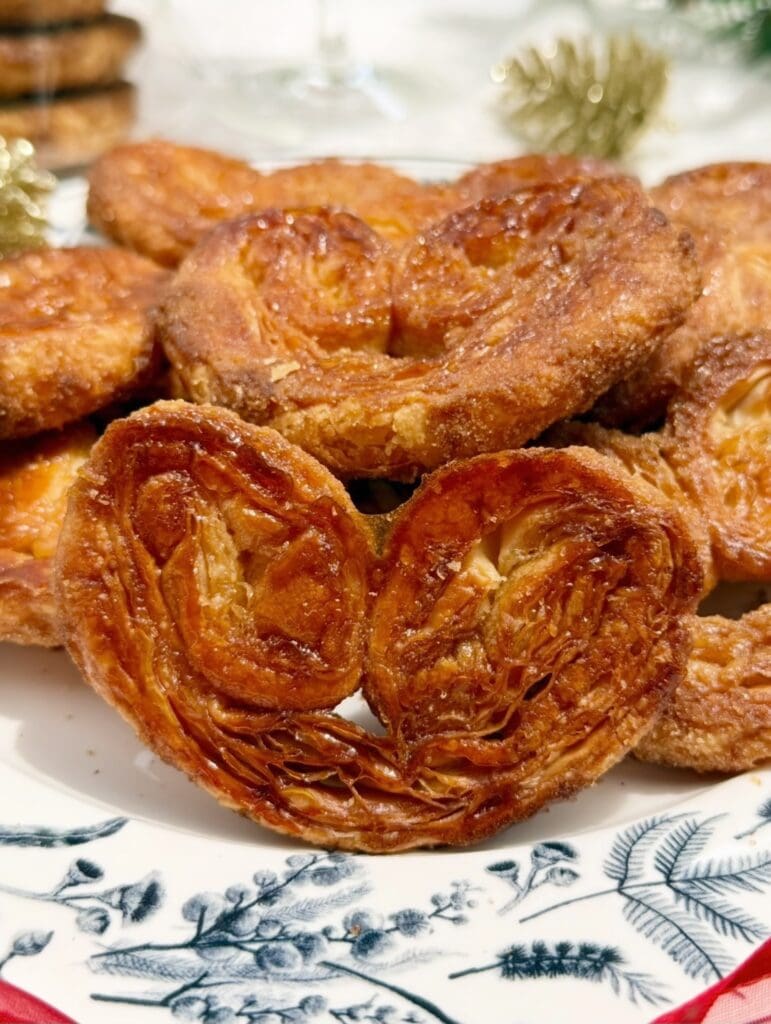 A close-up image of golden, flaky brown sugar palmiers