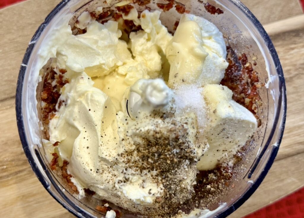 Adding the remaining ingredients to the bacon and onion mixture in a food processor.