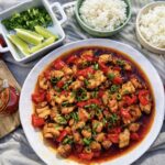Overhead view of honey sambal chicken with sticky sauce, red capsicum and spring onion garnish, served with rice