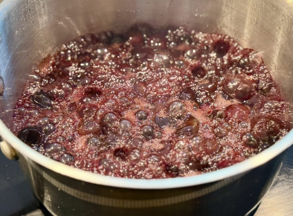 The cherries simmering with water and sugar in a saucepan