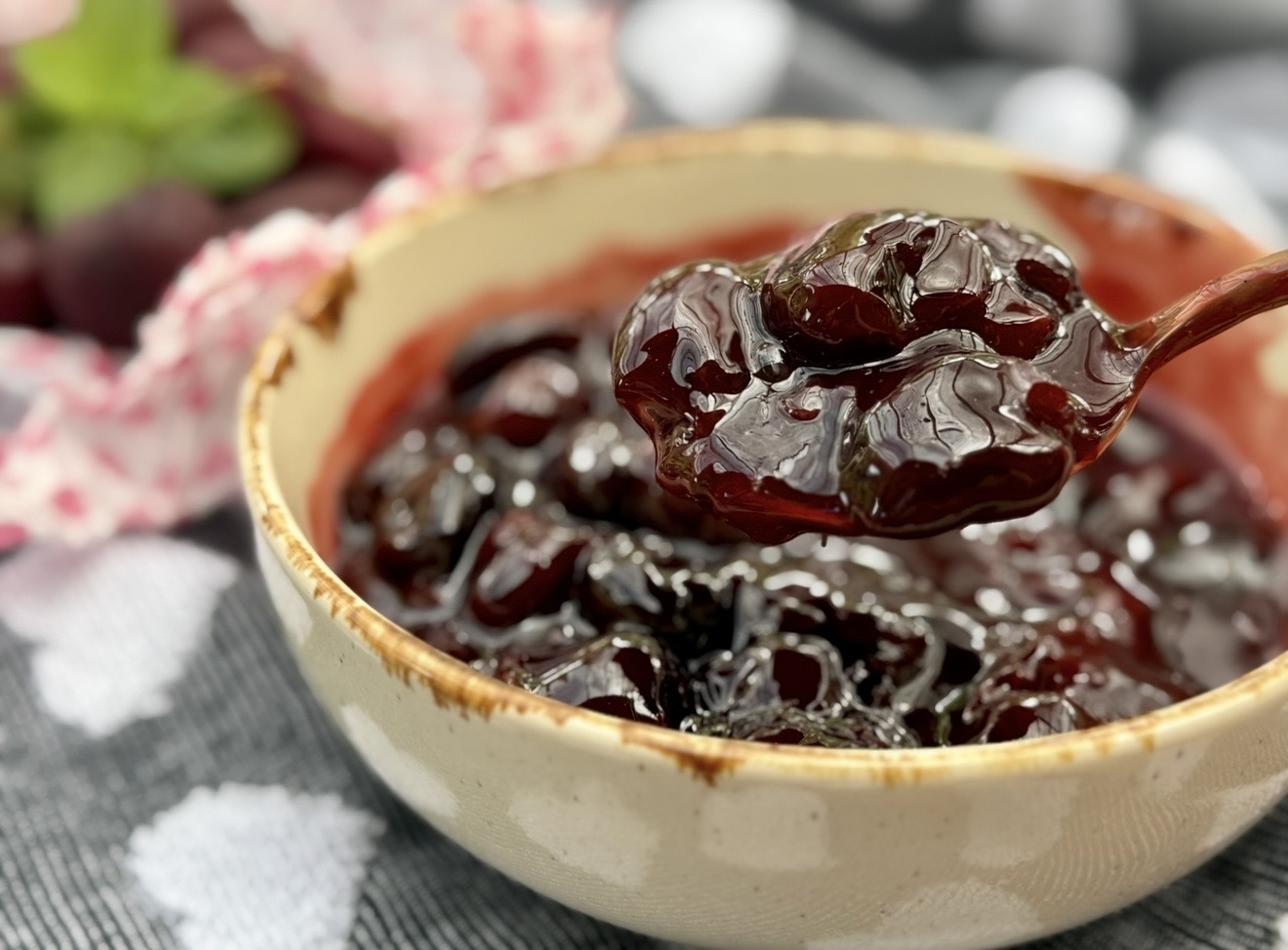 Close-up of glossy homemade cherry compote with whole cherries in a ceramic bowl.