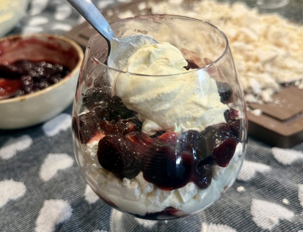 layering the cherry compote, meringue and whipped cream in a glass