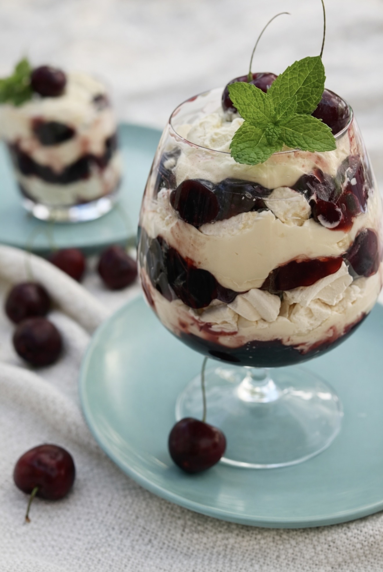Cherry Eton mess served in a glass with layers of cream, cherries, and meringue