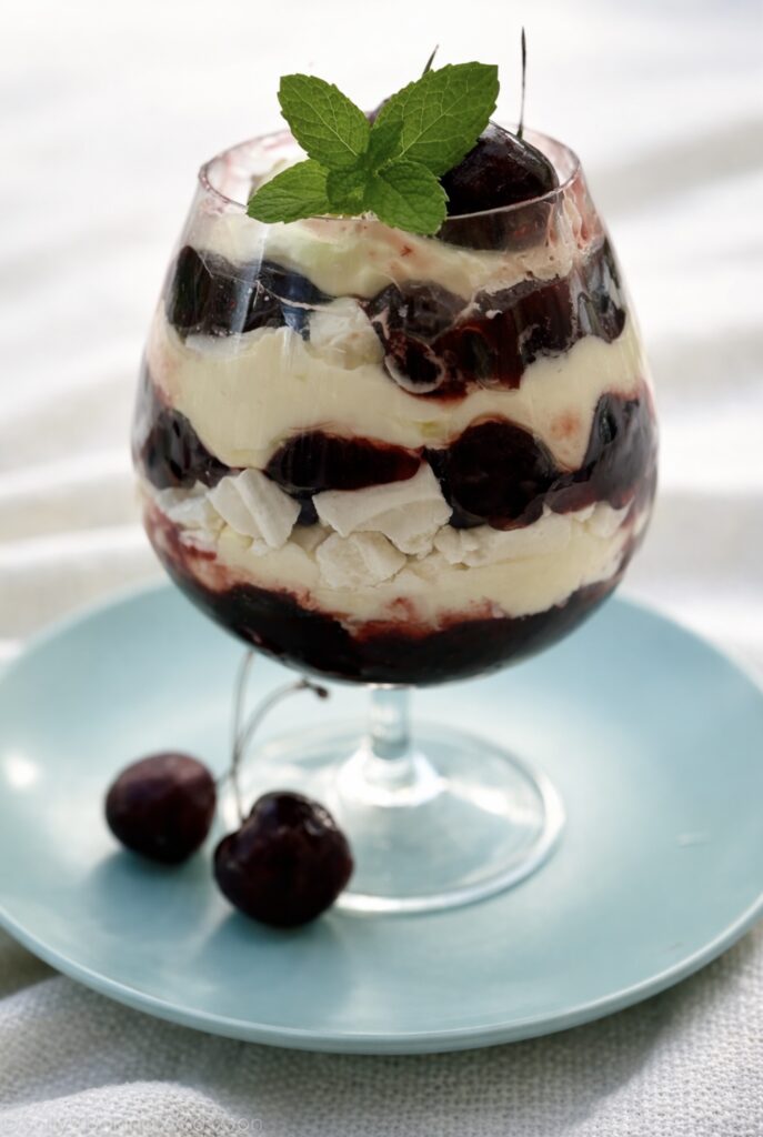Cherry Eton mess layered with whipped cream, cherry compote, and meringue in a glass
